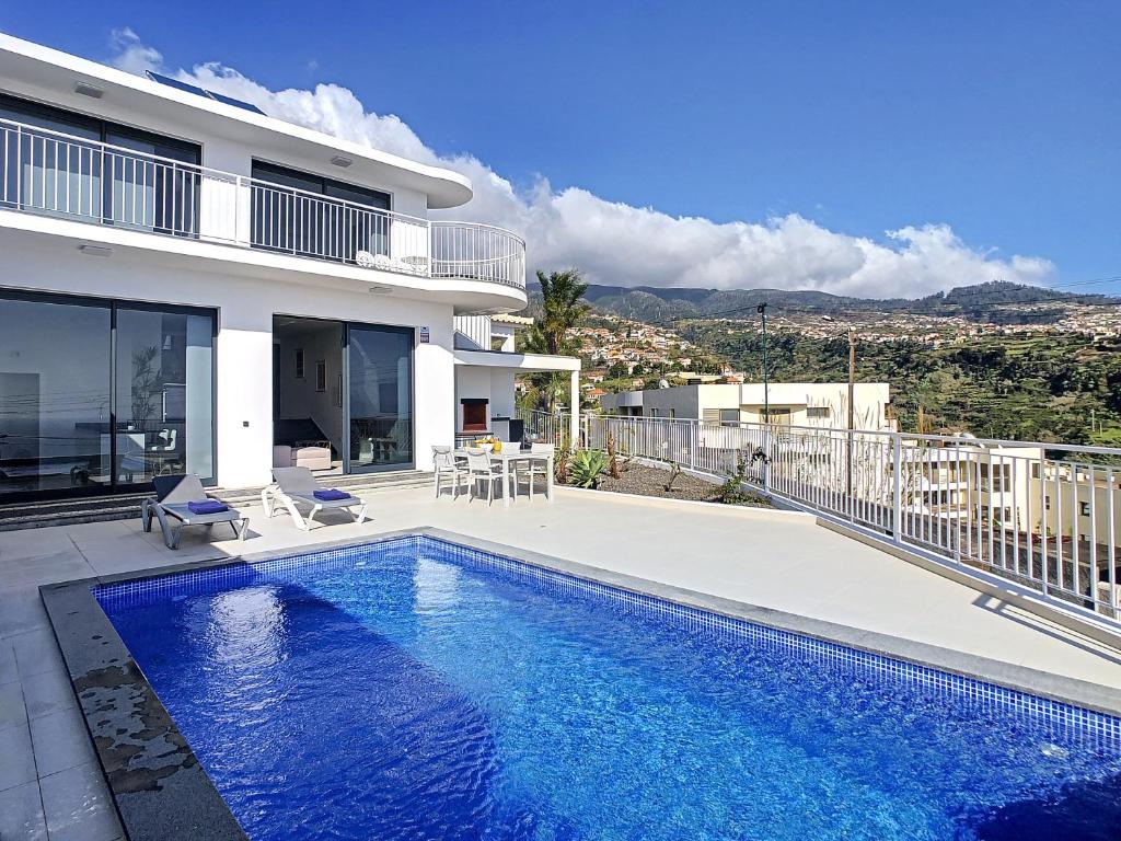 a villa with a swimming pool in front of a house at Casa dos Amores by LovelyStay in Calheta