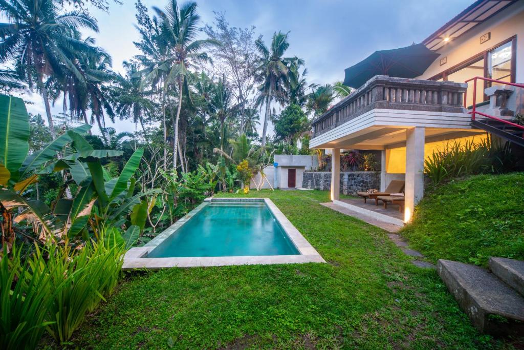 un patio trasero con piscina y una casa en Casa Priya Ubud, en Ubud