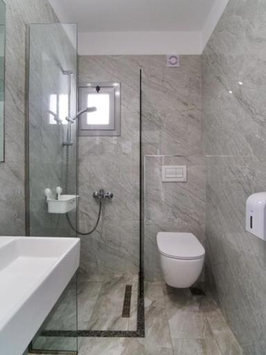 a bathroom with a shower and a toilet and a sink at Vironas Hotel in Himare