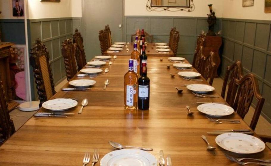 una larga mesa de madera con botellas de vino y platos en The Old School House, en Céaucé