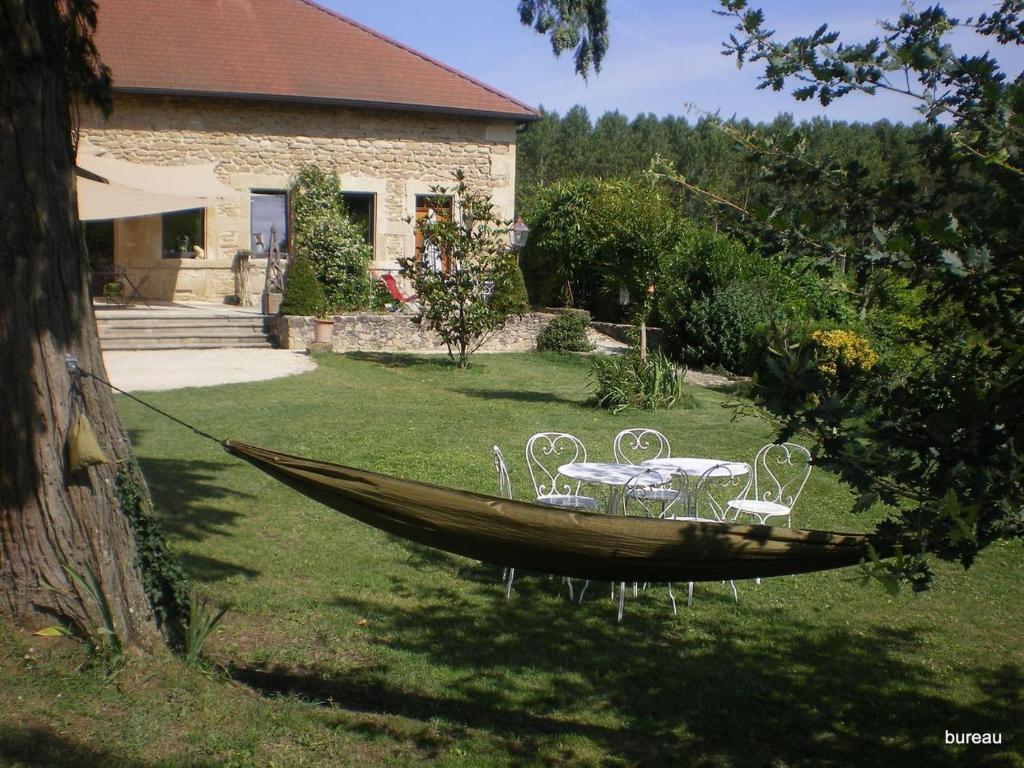 a wooden boat with chairs and a table in a yard at Petit Gite De La Renaissante in Peyrins