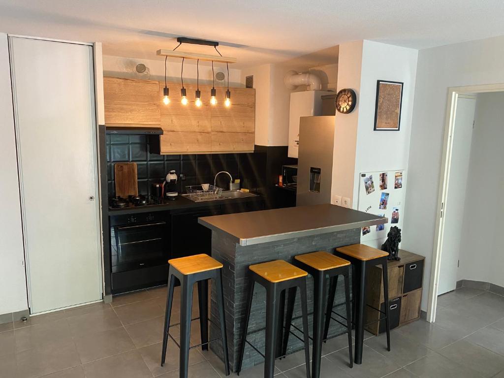 a kitchen with a counter with stools around it at Agréable Loft aux portes de bordeaux in Artigues-près-Bordeaux