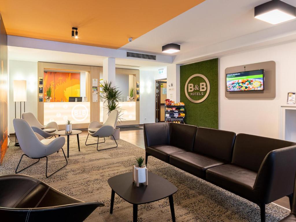 a lobby with a couch and chairs and a tv at B&B Hotel Essen in Essen