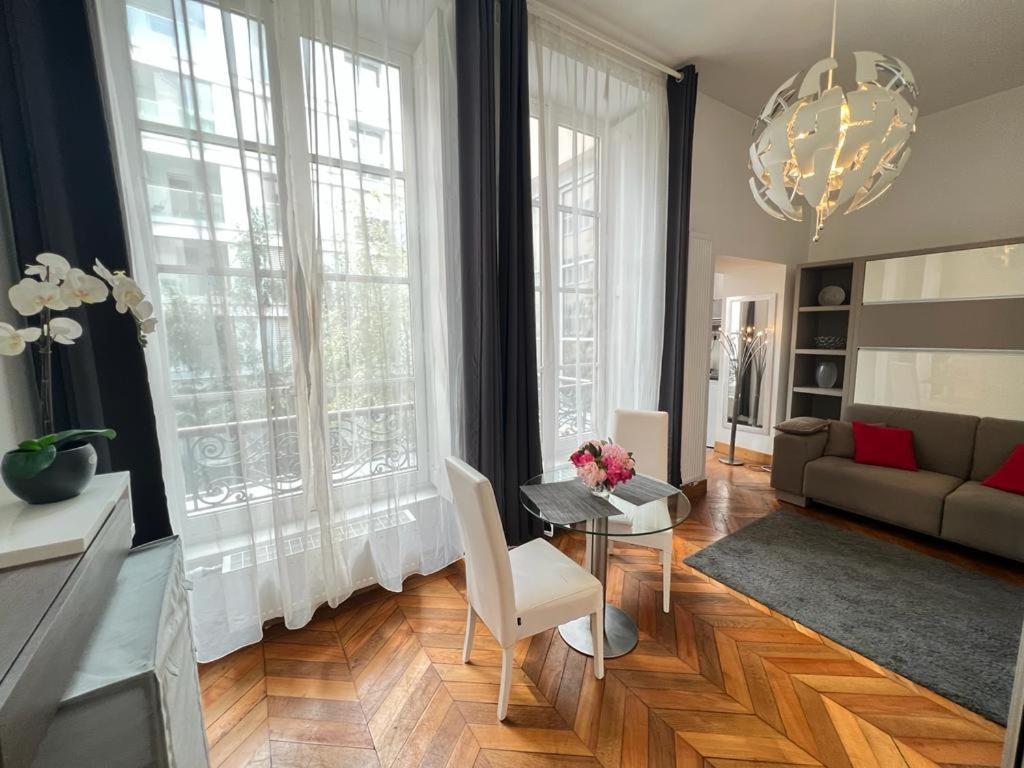 Le Lumineux - Le chic en hypercentre - Bellecour في ليون: غرفة معيشة مع أريكة وطاولة ونوافذ