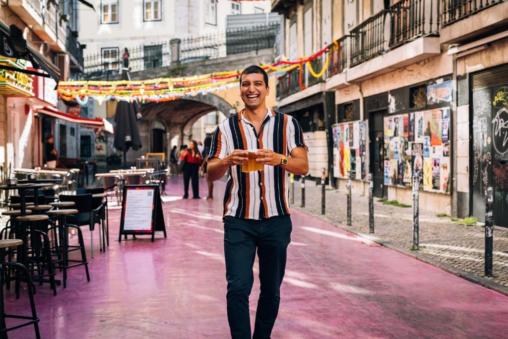 a man is walking down a city street at The House on the Pink Street in Lisbon in Lisbon