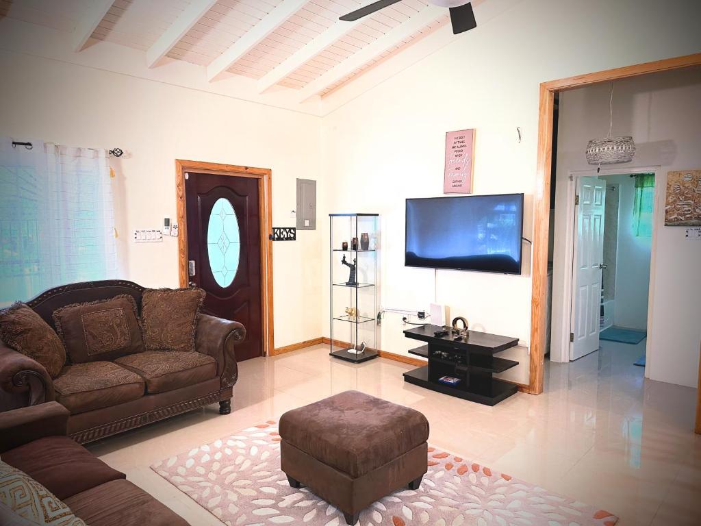 a living room with a couch and a flat screen tv at Sweet Holiday Haven in Ocho Rios