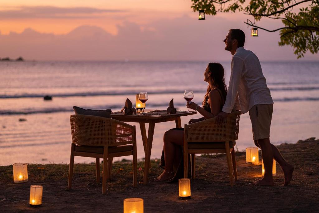 阿薩漢島的住宿－Bleu MATHIS Gili Asahan，坐在海滩桌子上的男人和女人