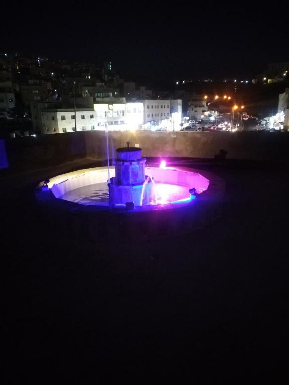 Una fuente con luces púrpuras en una ciudad por la noche en شقة فاخرة مع مطل, en Amán