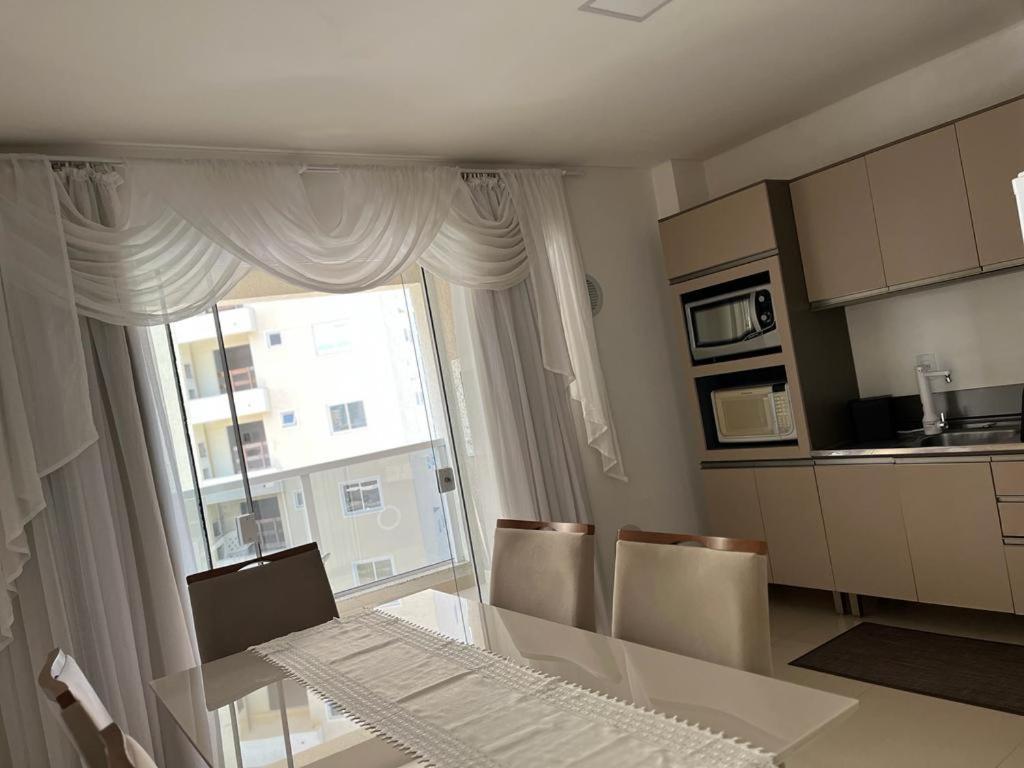 伊塔佩馬的住宿－Apartamento à 400m do mar，厨房配有桌椅和窗户。
