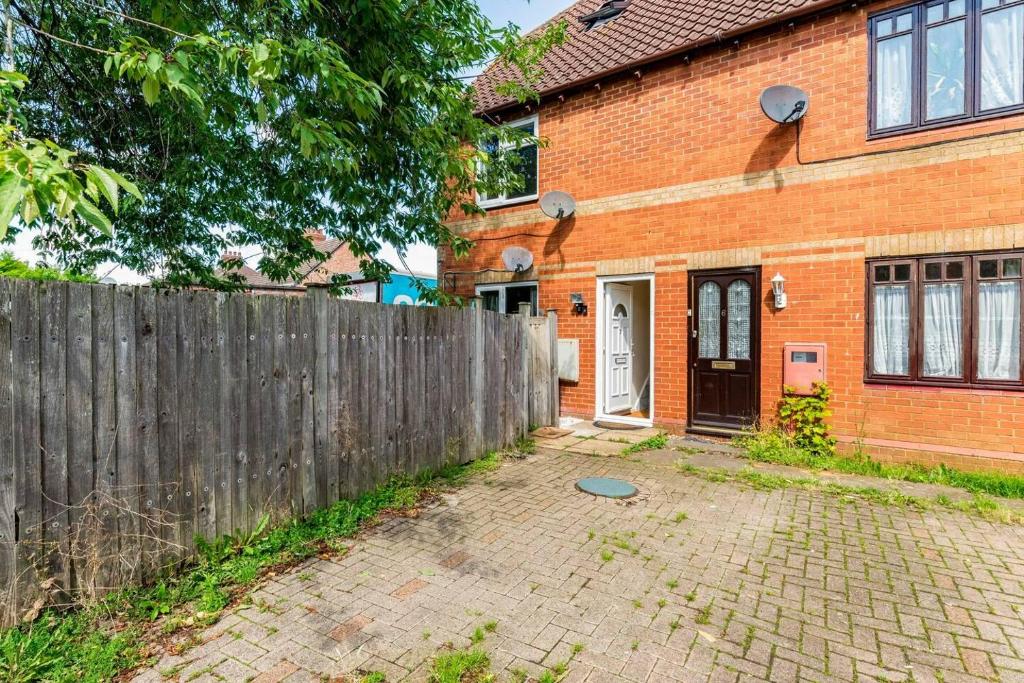 a brick house with a wooden fence in front of it at Immaculate 2 - Bedroom House in Milton Keynes in Milton Keynes