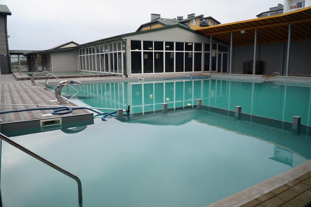 a swimming pool with blue water in front of a building at Готель Гармонія. Термально-оздоровчий комплекс. in Mynay