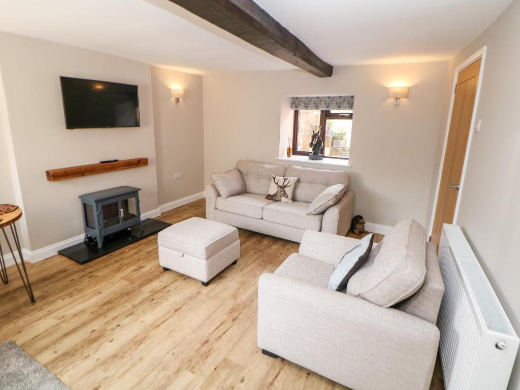 a living room with two couches and a tv at Smithy Cottage in Dronfield
