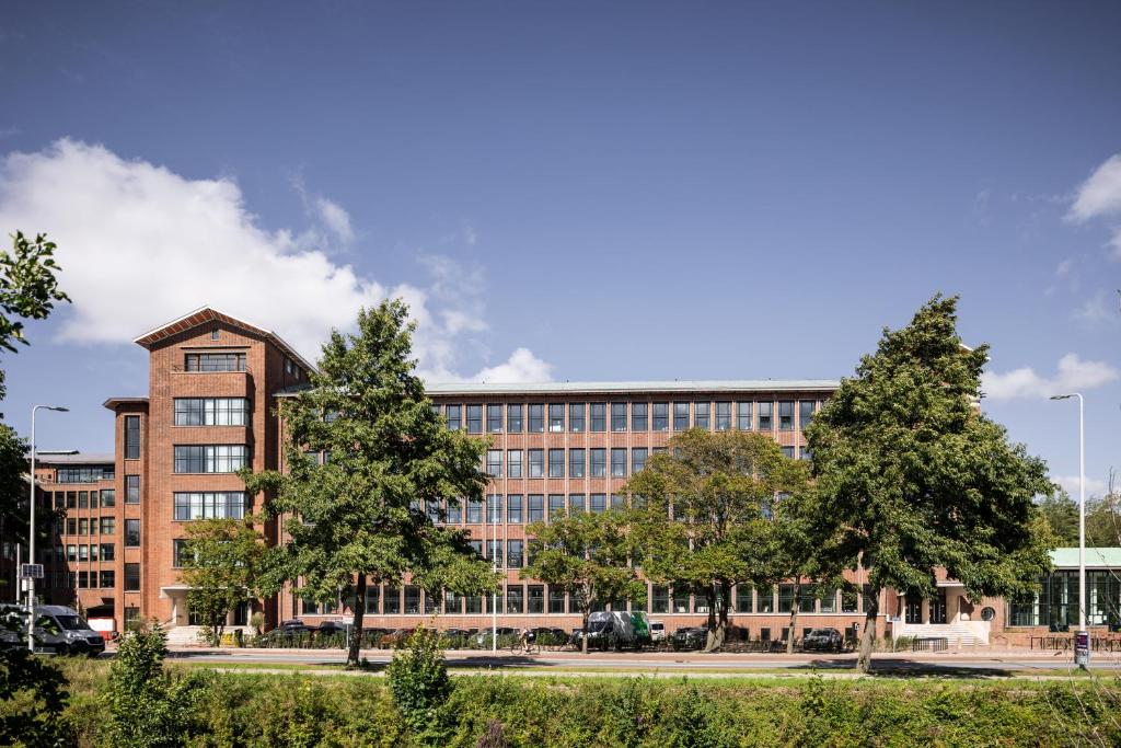 un edificio de oficinas con árboles delante de él en Plesman Residences en Scheveningen