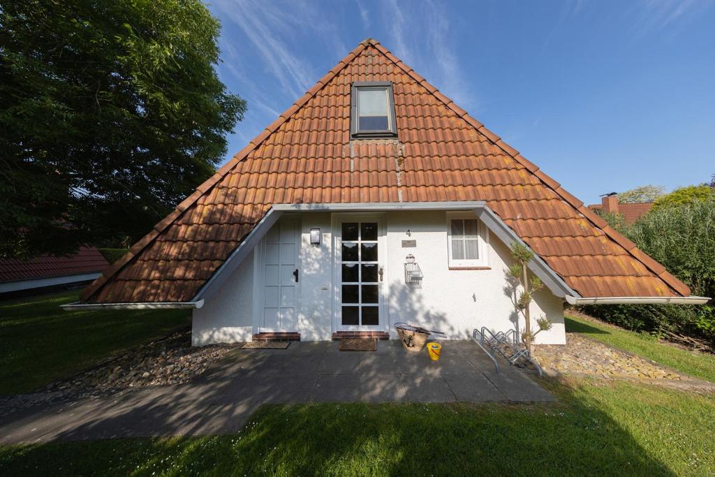 une petite maison blanche avec un toit rouge dans l'établissement WS4 - Strandvogt 2 Komfort, à Dorum Neufeld