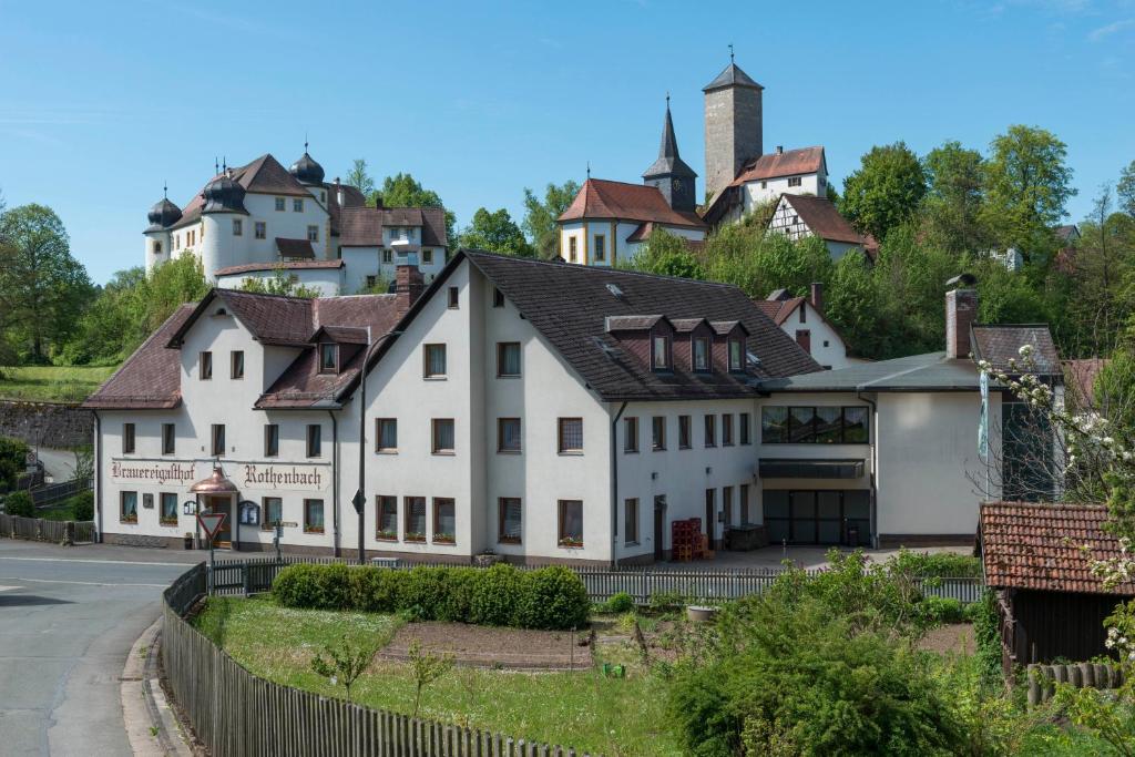 a white house with a village in the background at Brauereigasthof Rothenbach in Aufseß