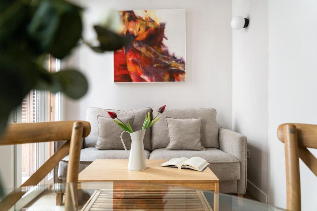 salon z kanapą i wazą z kwiatami w obiekcie Room Canalejas w Madrycie