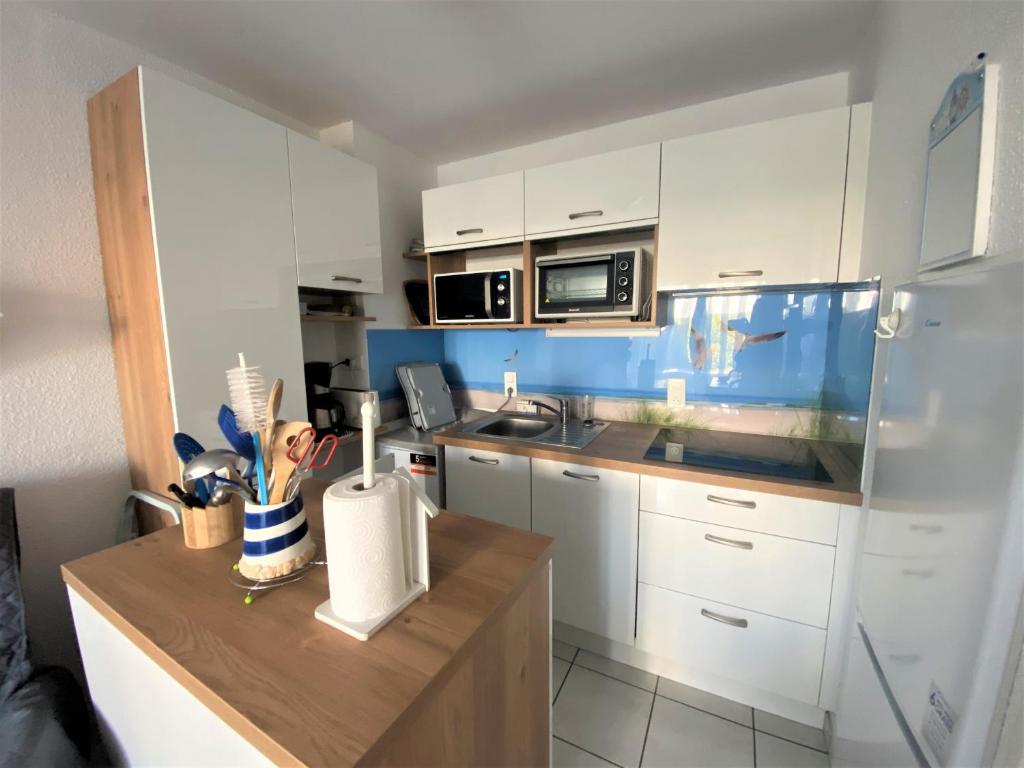 カルナックにあるReflets, appartement à Carnacのキッチン(白いキャビネット、木製カウンタートップ付)