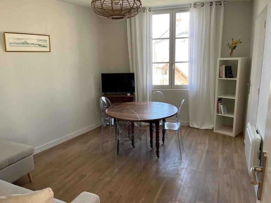 a living room with a table and a television at Appartement centre Saumur bord de Loire Les marronniers in Saumur