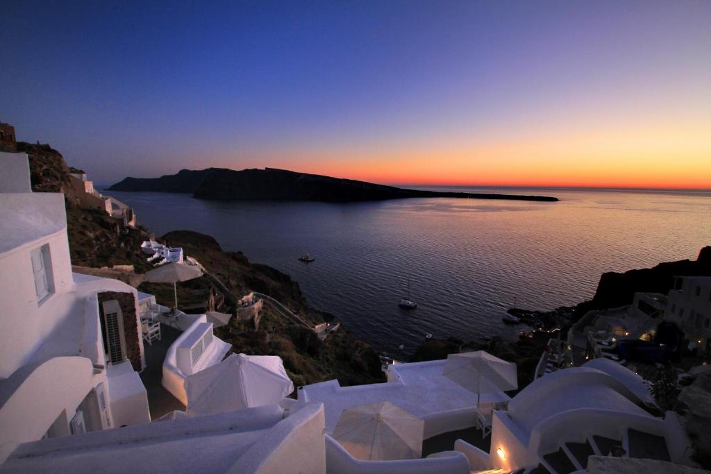 vista sul tramonto sull'acqua con edifici bianchi di Finesse Suites a Oia