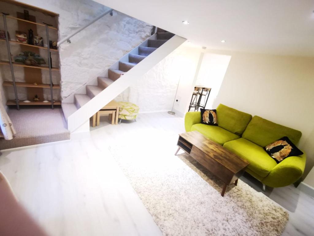 a living room with a green couch and a staircase at 2-level apartment in Aberdeen