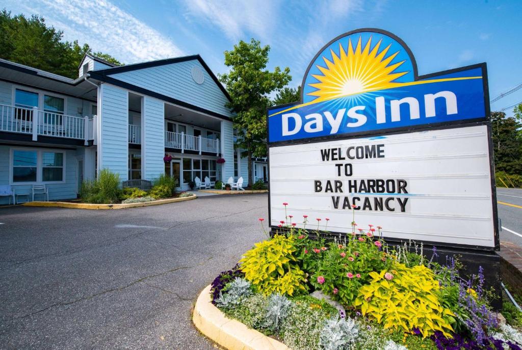 a sign for days inn with flowers in front of a building at Days Inn by Wyndham Bar Harbor in Bar Harbor