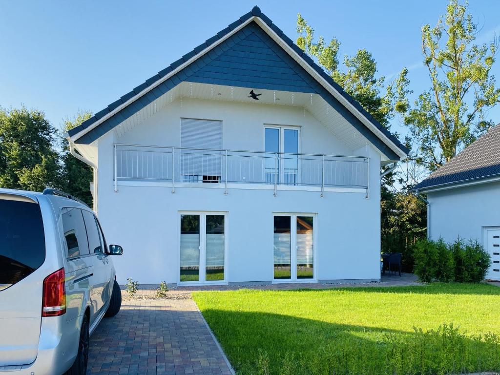 una casa blanca con una furgoneta estacionada frente a ella en Seeglück 1 am Tollensesee, en Groß Nemerow