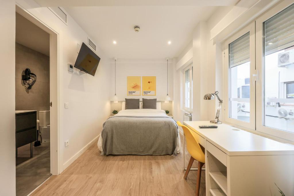 1 dormitorio con cama, escritorio y escritorio en AmazINN Places Chamberi, en Madrid