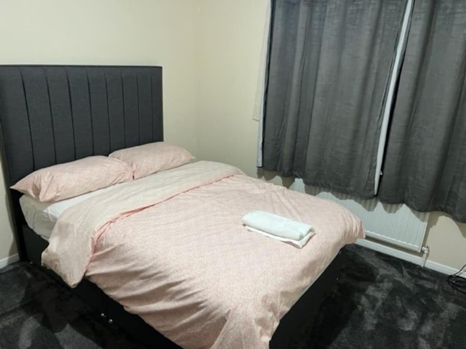 Una cama con un teléfono blanco encima. en 3 bedroom mid terraced house (2 double & 1 single), en Grays