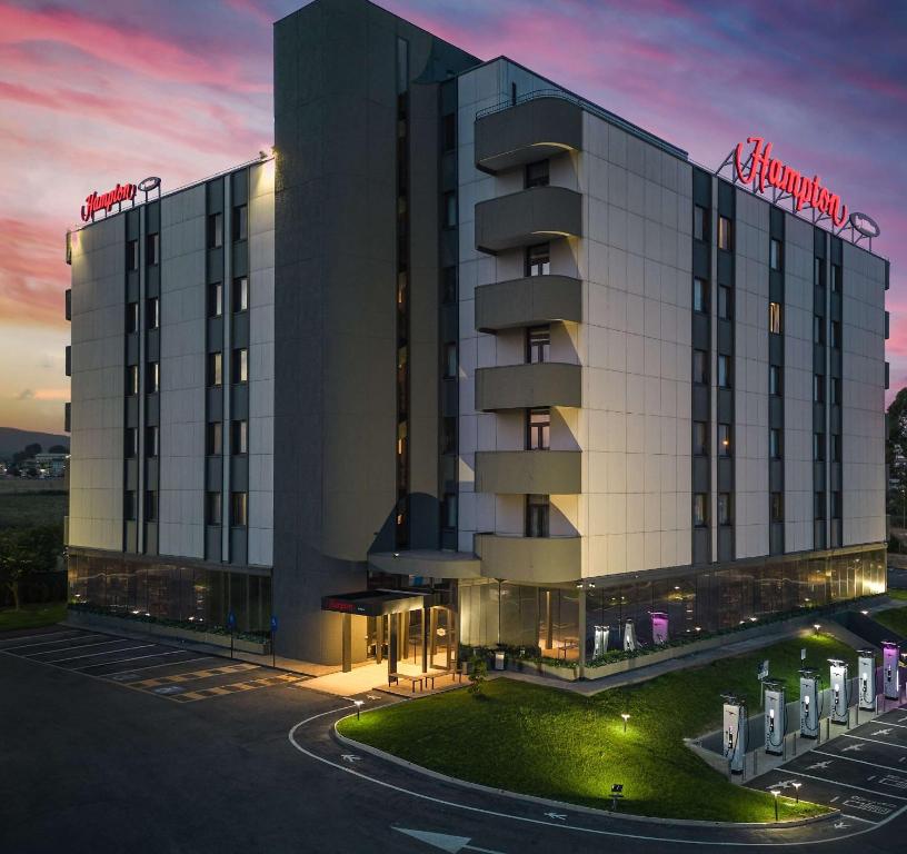 a rendering of a hotel building at dusk at Hampton by Hilton Rome North Fiano Romano in Fiano Romano