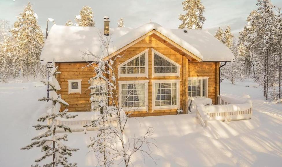 una cabaña de madera en la nieve con nieve en Hallahaukka, en Ivalo