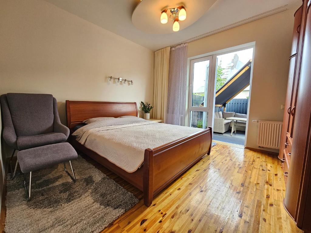 a bedroom with a bed and a chair and a window at Zeliūga Apartments in Palanga