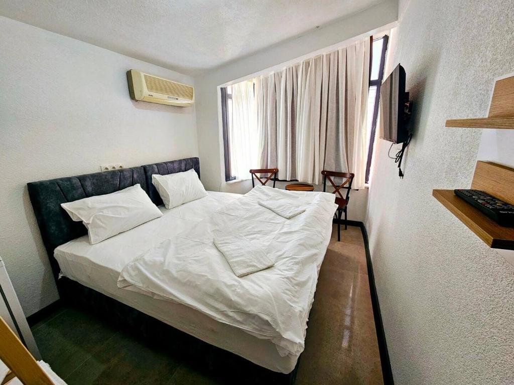 Noya Suites في إسطنبول: غرفة نوم بسرير وملاءات بيضاء ونافذة