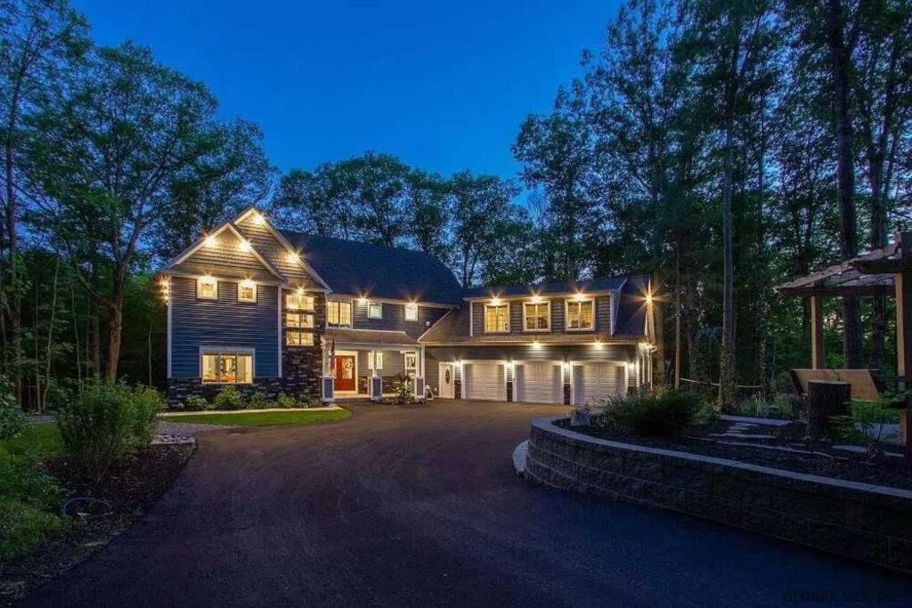 a large house with lights on the front of it at The Athena Hideaway - hottub, firepit, lake & racetrack in Saratoga Springs