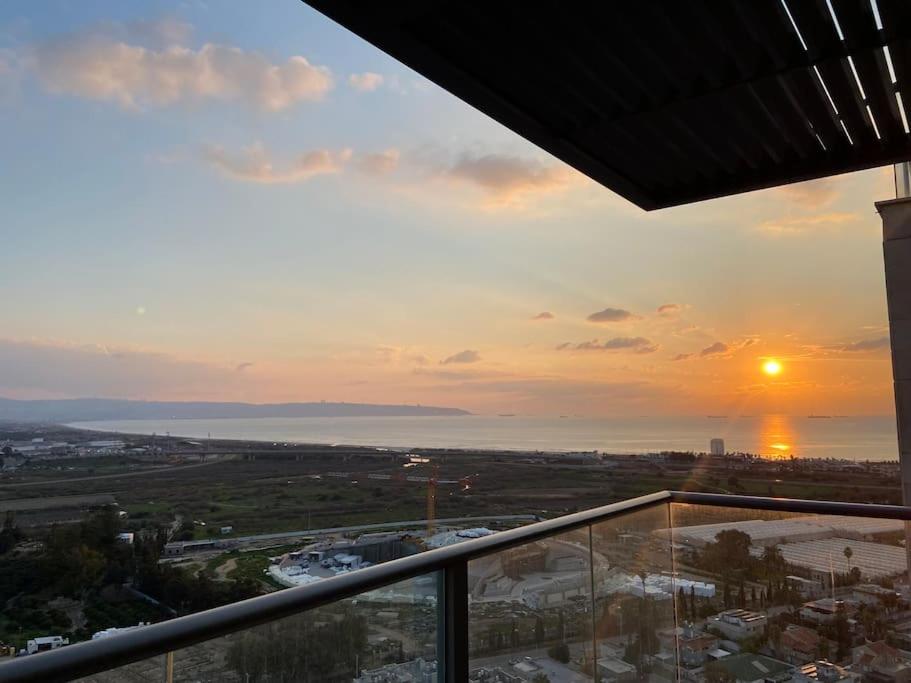 einen Blick auf den Sonnenuntergang vom Balkon eines Gebäudes in der Unterkunft דירת גג ים עכו חיפה נוף מרהיב in Akkon