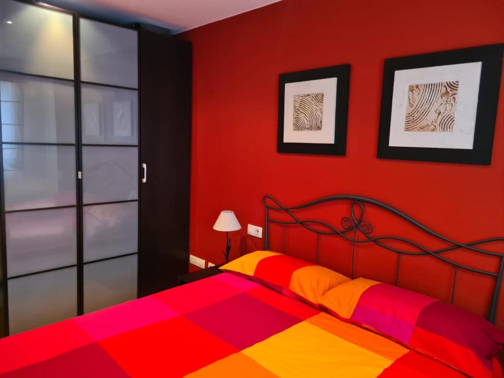 ein rotes Schlafzimmer mit einem Bett mit einer bunten Decke in der Unterkunft Acogedor apartamento Estacion de esqui San Isidro in San Isidro