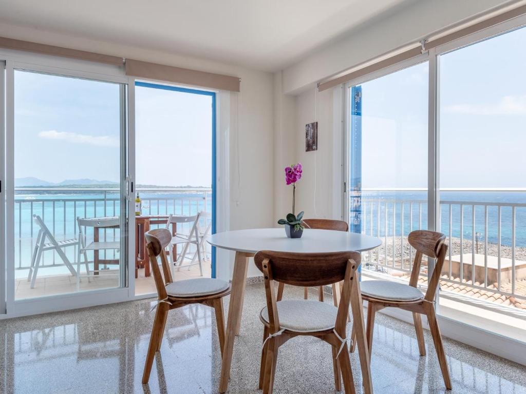 een eetkamer met een tafel en stoelen en grote ramen bij Apartamento rocamar in S'Illot