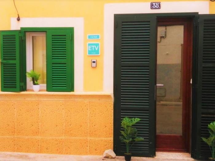 un edificio con persianas verdes y una puerta en Can Tassi, en Porto Cristo