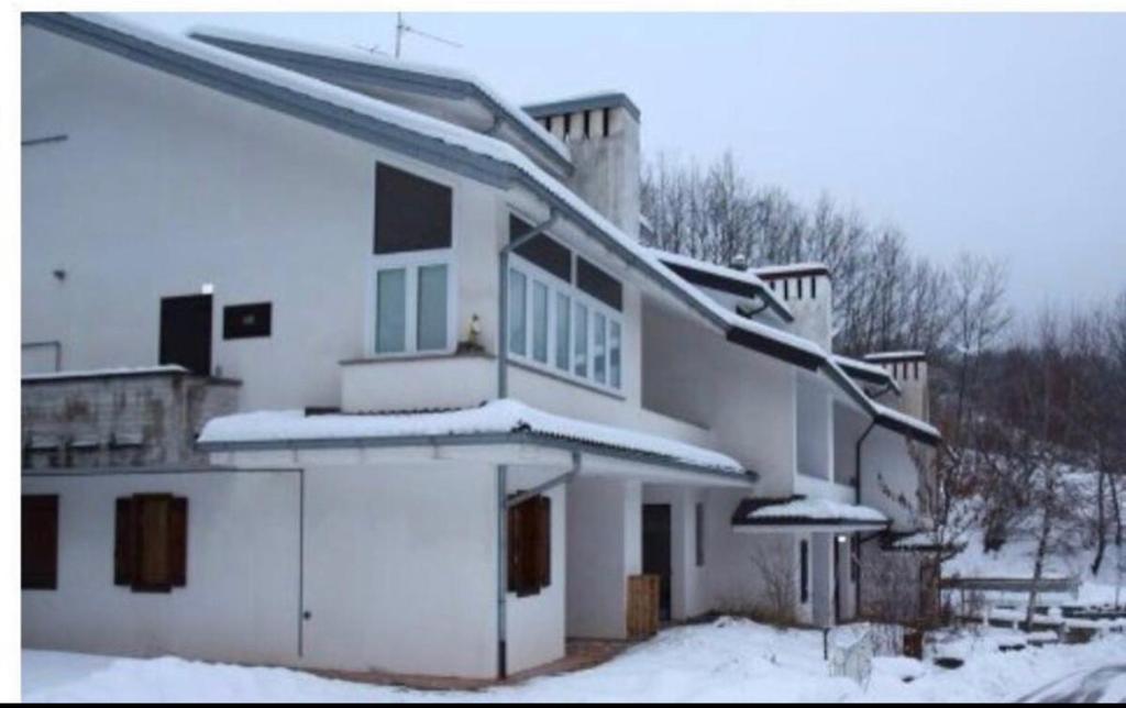 una casa blanca con nieve en el techo en Bilocale per gli amanti dello sci, en Riolunato