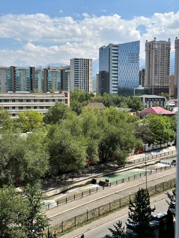 uma cidade com um parque com árvores e edifícios em Просторная квартира в верхней части мегаполиса em Almaty