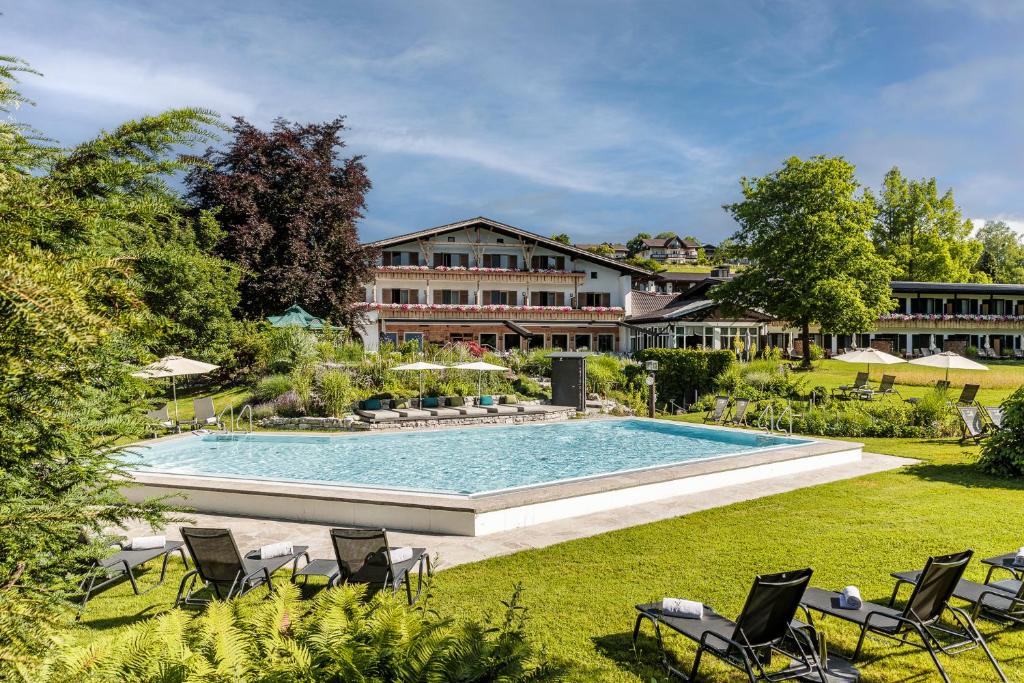 a pool with chairs and a building in the background at Alpenhof Murnau in Murnau am Staffelsee