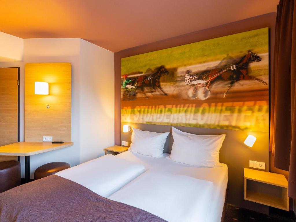 メンヒェングラートバッハにあるB＆B ホテル メンヒェングラートバッハのベッド付きの客室で、壁には絵画が飾られています。
