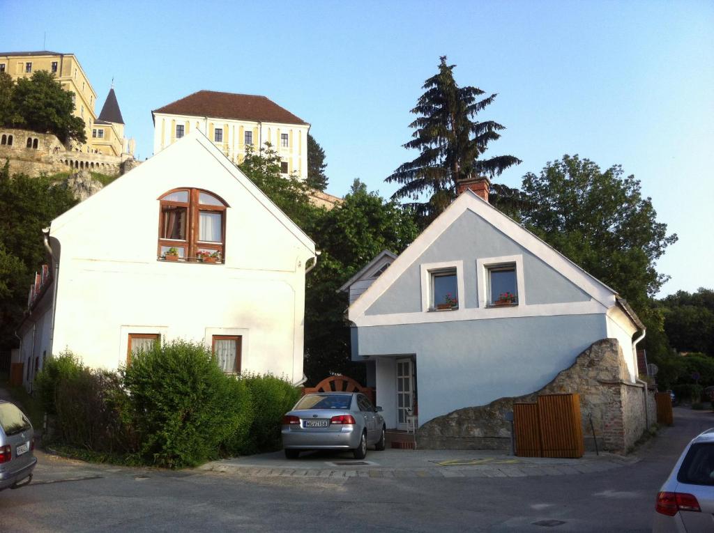 una casa bianca con una macchina parcheggiata in un parcheggio di Galeria Villa a Veszprém