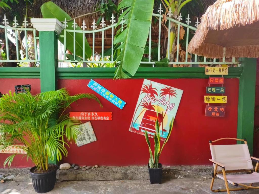 a red wall with signs and a chair and plants at 天堂鸟花园客栈 in Luang Prabang
