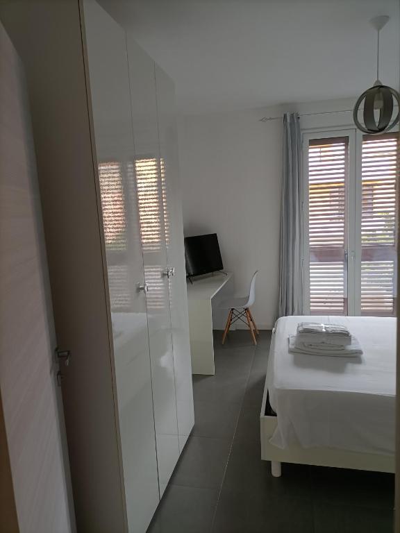 biała sypialnia z łóżkiem i przesuwnymi szklanymi drzwiami w obiekcie B&B Al Porticciolo w mieście Marsala