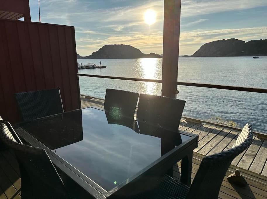 a table and chairs on a deck near the water at Nydelig ferieleilighet på bryggekanten in Korshamn