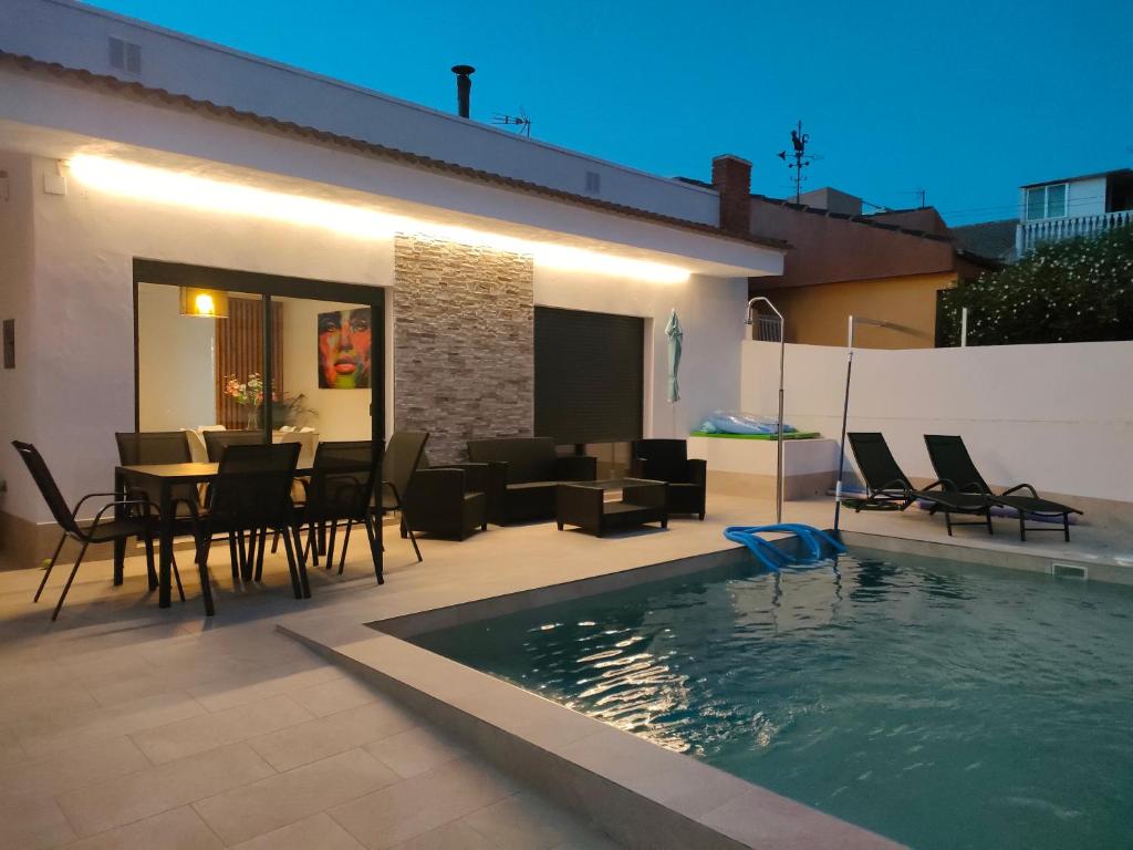 eine Terrasse mit einem Tisch und Stühlen sowie einem Pool in der Unterkunft Villamolinos, villa con piscina privada. in San Pedro del Pinatar