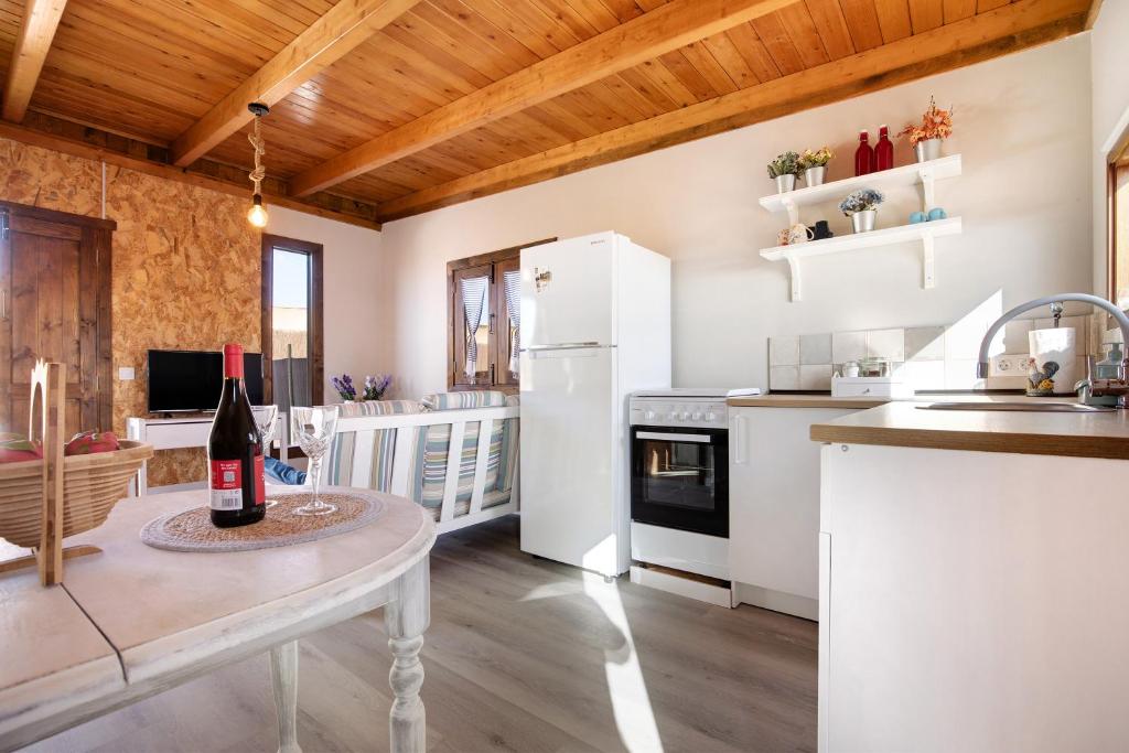 a kitchen with white appliances and a table with a bottle of wine at Casa Barranco de la Sal in Puerto del Rosario