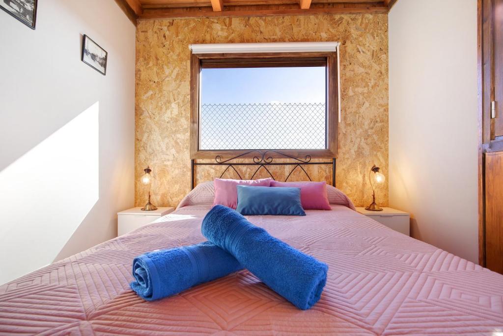 a bedroom with a large bed with blue pillows at Casa Barranco de la Sal in Puerto del Rosario