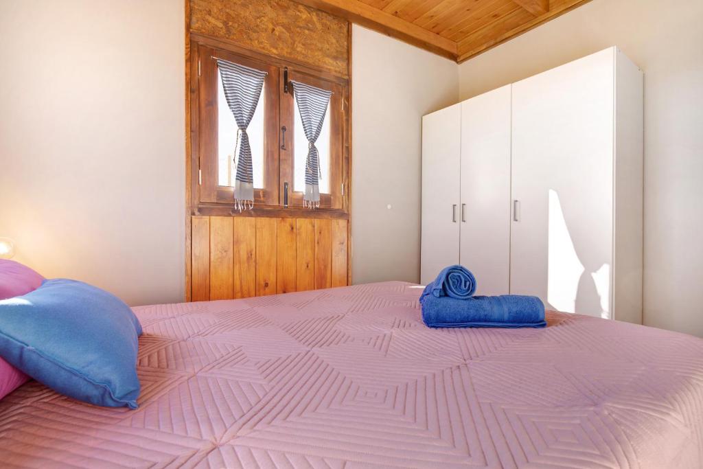 a bedroom with a pink bed with blue pillows on it at Casa Barranco de la Sal in Puerto del Rosario