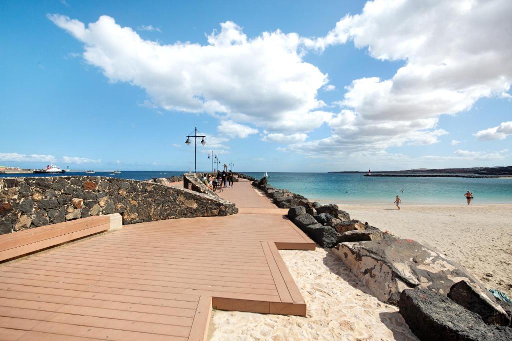 a boardwalk on a beach with people walking on it at Casa Barranco de la Sal in Puerto del Rosario